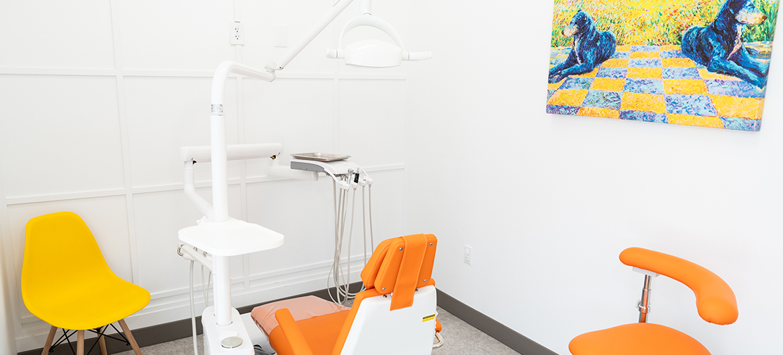 Bright orange pediatric dental exam room with playful artwork.