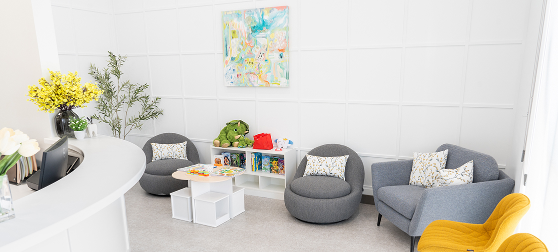 A cozy pediatric dental waiting room with colorful seating and children's books.